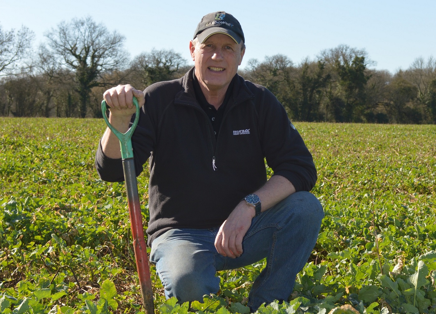 a man sitting in a field holding a stick